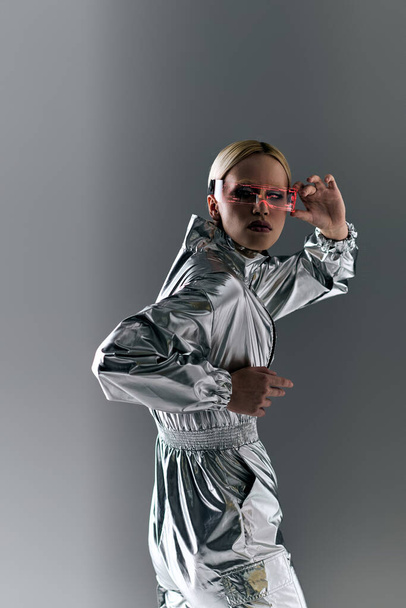 bizarre woman with sci fi glasses in futuristic attire doing robotic motions and looking at camera - Foto, immagini