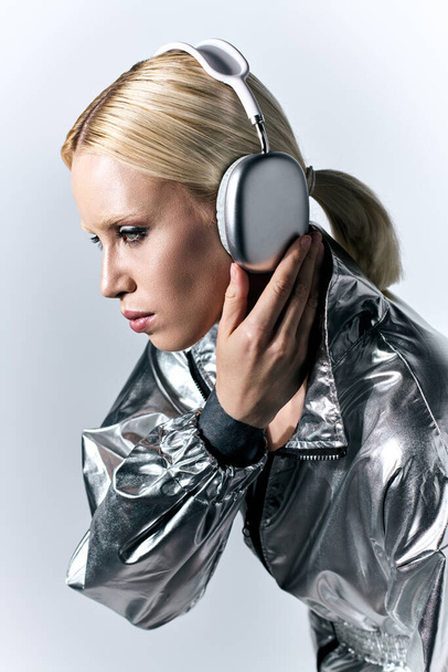 buitengewoon goed uitziende vrouw met koptelefoon in futuristische zilveren kleding genieten van muziek - Foto, afbeelding