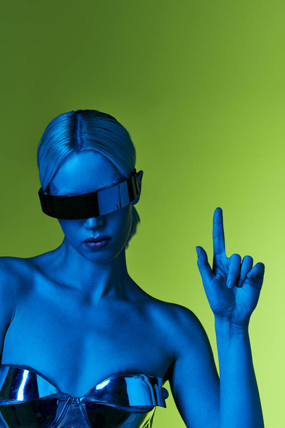 παράξενη γυναίκα σε ασημί ρομποτική ενδυμασία με γυαλιά ηλίου sci fi ποζάρουν σε φώτα σε πράσινο φόντο - Φωτογραφία, εικόνα