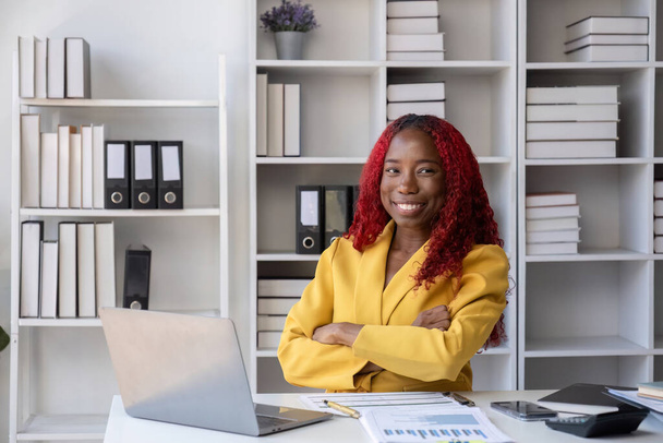 Африканська американська бізнес-леді, яка щаслива робити бухгалтерські та фінансові роботи на своєму столі в офісі.. - Фото, зображення