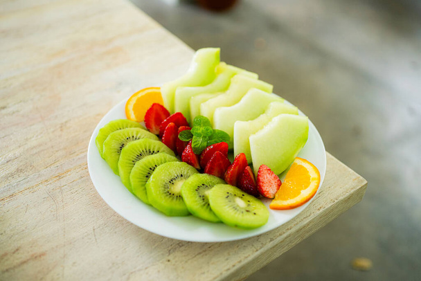 mixed fruit plate containing melon, strawberries, oranges and kiwi. - Photo, Image