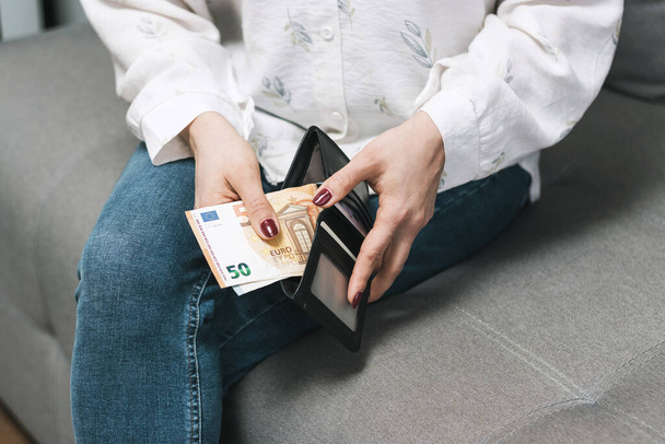 Женские руки вынимают деньги из кошелька, банкноты евро. - Фото, изображение