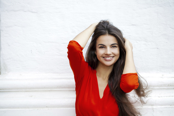 Happy young woman in red dress against the background of a block - Foto, imagen
