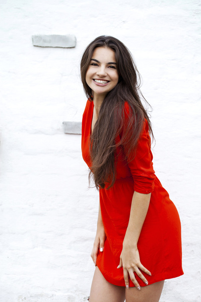 Happy young woman in red dress against the background of a block - Фото, зображення