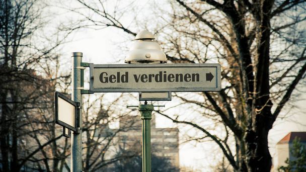 obraz pokazuje drogowskaz i znak, który pokazuje kierunek zarabiania pieniędzy w języku niemieckim. - Zdjęcie, obraz