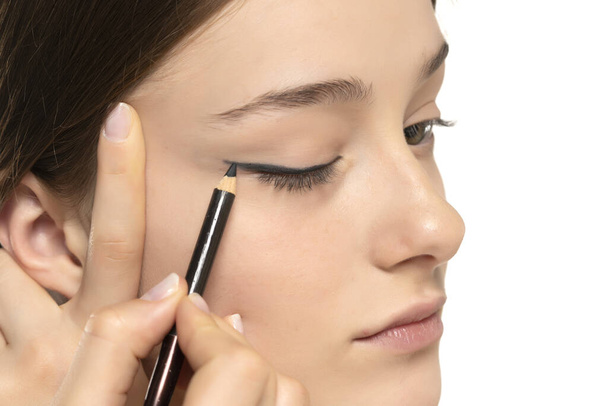 nainen soveltamalla eyeliner silmäluomen kynällä valkoinen studio tausta - Valokuva, kuva