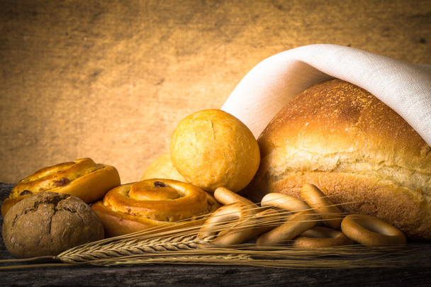 Ekmek ürün çeşitliliği ve buğday kulaklara eski bir ahşap masa. Tonda - Fotoğraf, Görsel