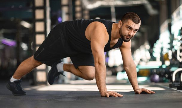 Motivated Muscular Man Making Running Plank Exercise While Training In Gym, Confident Handsome Male Athlete In Activewear Working Out In Modern Sport Club Interior, Enjoying Fitness Lifestyle - Photo, Image