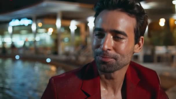 Party guy enjoy communication at night water pool club closeup. Handsome latin gentleman talking laughing at outdoors evening hangout. Smiling unshaven macho in glamorous red suit relaxing at poolside - Footage, Video