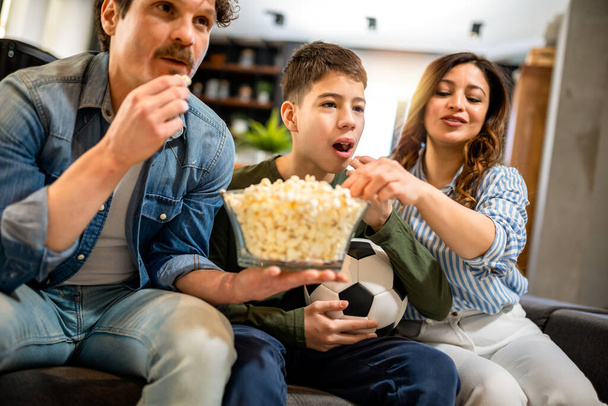 Latino famille regarde match de football et manger popcorn.They sont acclamations pour leur équipe. - Photo, image