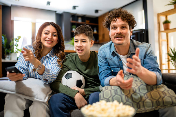 Сім'я латиноамериканців спостерігає за футбольним матчем і їсть попкорн.. - Фото, зображення