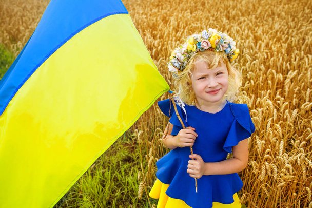 Ukrán lány kék és sárga zászlós kijelzővel. lány gazdaság zászló Ukrajna. Kék sárga zászló Ukrajna címerrel a kezében gyermek a függetlenség napján és a zászló napján - Fotó, kép
