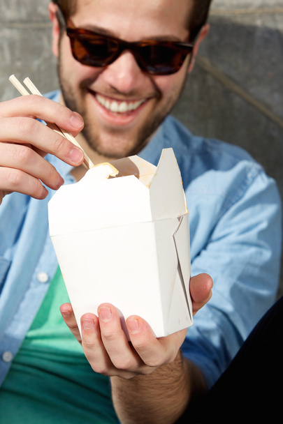 Cool guy eating takeaway food with chopsticks - Фото, изображение