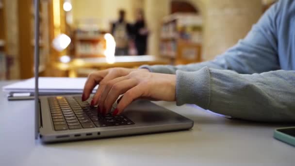 Detailní záběr ženy ruce psaní na klávesnici pomocí notebooku na veřejném místě, spolupráce. Digitální nomád pracuje na dálku. Studium dospělých ve veřejné knihovně Technologie ve vzdělávání a podnikání - Záběry, video