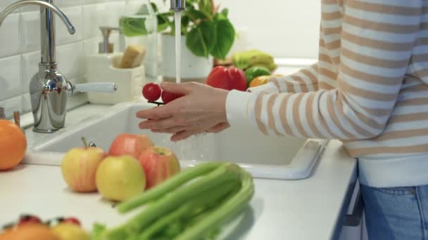 Eller musluk suyunun altında kiraz domateslerini yıkıyor. Elma, kereviz, masada duran biber. Salata pişirmek için vitamin dolu sağlıklı organik taze sebzeler. Arınma, diyet ve enerji için besin - Video, Çekim