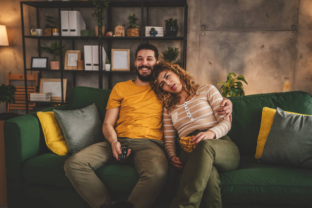 Couple man and woman caucasian husband and wife or boyfriend and girlfriend sit on the sofa bed at home watch tv movie series with hold remote controller happy smile bonding love family concept - Photo, Image