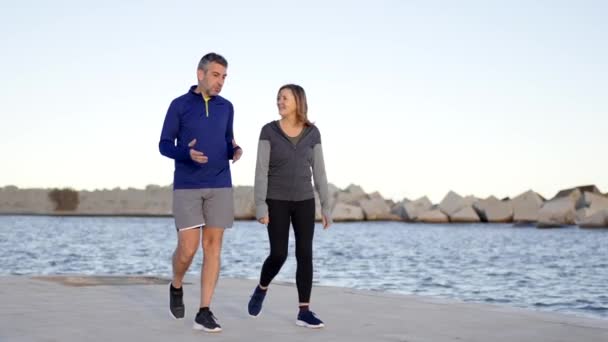 Videó egy sportoló idős aktív párról, akik beszélgetnek és sétálnak a sétányon - Felvétel, videó
