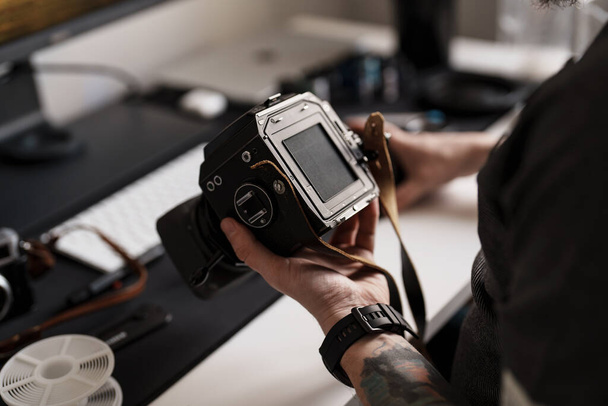Un hombre adulto está absorto en ajustar los ajustes en una cámara de formato medio, destacando la atención meticulosa al detalle en un estudio profesional - Foto, imagen
