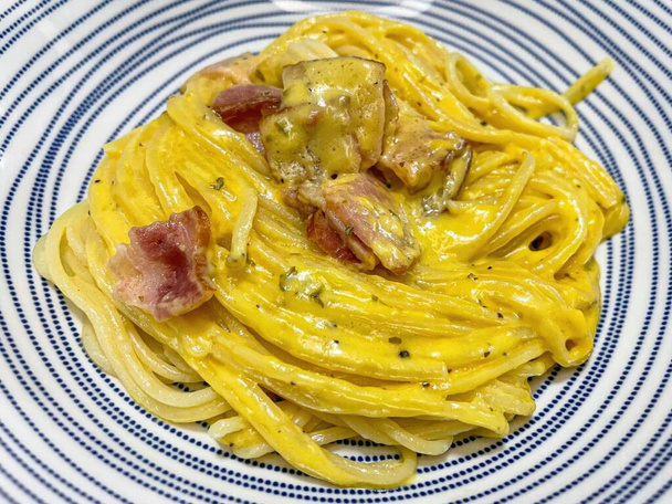 Спагетти карбонара с беконом и сыром на голубой тарелке. - Фото, изображение