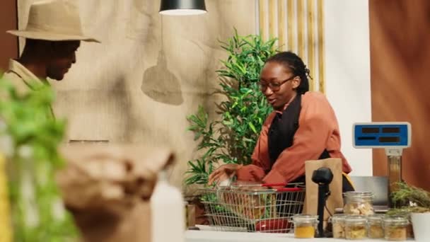 Αφρο-αμερικανίδα πελάτισσα χαιρετάει στο ταμείο στην τοπική αγορά αγροτών, σταθμίζοντας τα φρέσκα προϊόντα για τον άντρα. Αγορές πελατών για φυσικά βιολογικά τρόφιμα εναλλακτικές λύσεις. Κάμερα Α. - Πλάνα, βίντεο