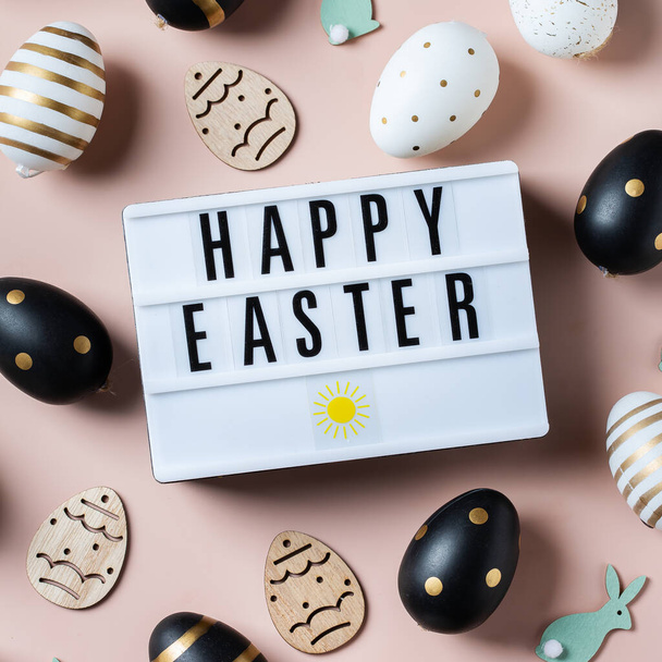 Happy Easter frame met gouden, witte, zwarte gestippelde en gestreepte eieren op een roze achtergrond. Bovenaanzicht, vlak. Moderne Pasen wenskaart - Foto, afbeelding