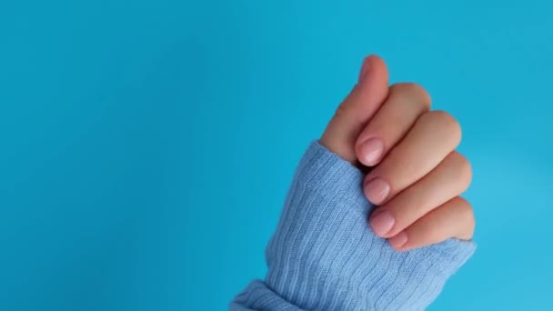 Mani curate donna, unghie beige alla moda. Primo piano di unghie curate di mano femminile in maglione blu su sfondo blu. Stile invernale o autunnale del concetto di nail design. Trattamento di bellezza. - Filmati, video
