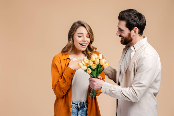 Portrait excited, smiling woman and man wearing stylish colorful clothes, holding mobile phone, using mobile app, win money standing isolated on pink background. Sport betting concept, online shopping  - Photo, Image