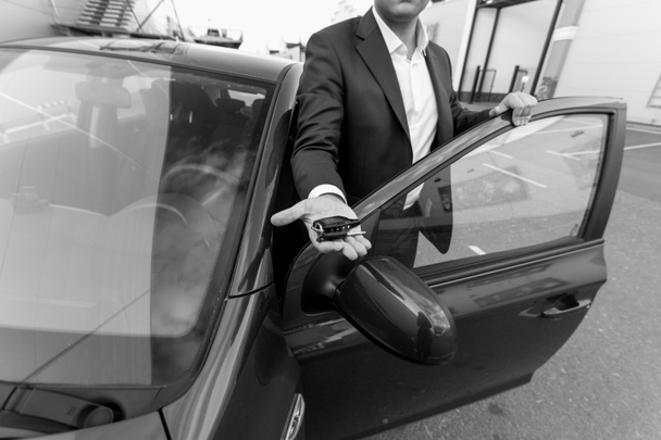 Black and white closeup of car sales manager holding key on hand - Foto, Bild