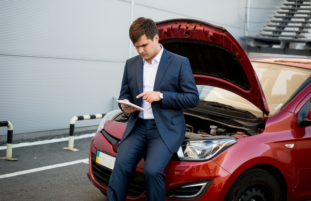 businessman sitting on hood of broken car and searching how to f - Photo, Image