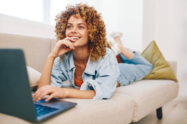 Kybernetické připojení: Usmívající se žena pracující na notebooku v útulném obývacím pokoji - Fotografie, Obrázek