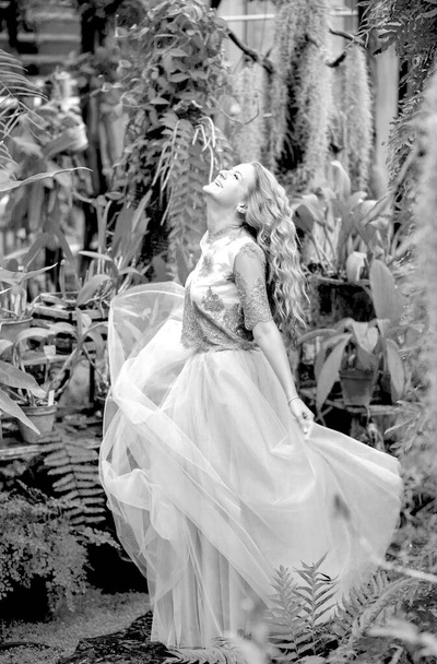 Black and white photo of a stunning girl in a wedding dress, blonde with long curls circling in nature. Happiness concept - Photo, Image
