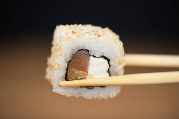 delicious traditional Japanese sushi and rolls on a plate holding chopsticks - Photo, Image