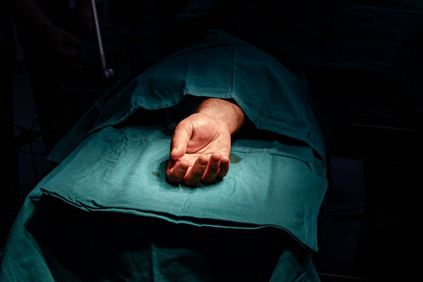 Ręka pacjenta na stole operacyjnym gotowa do operacji na sterylnej sali operacyjnej. - Zdjęcie, obraz