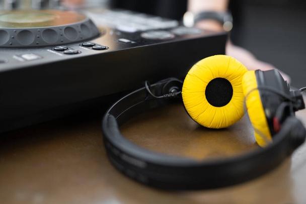 schicke gelbe DJ-Kopfhörer in der Nähe des Controllers auf dem Tisch - Foto, Bild