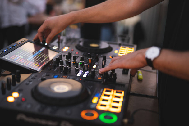 a DJ plays music on a controller at a party - Zdjęcie, obraz