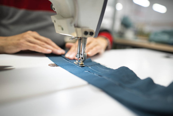 робітники на промисловій швейній фабриці шиють одяг на швейній машинці - Фото, зображення