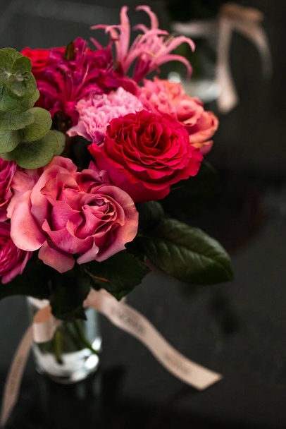 Яскравий букет з рожевих і червоних троянд у скляній вазі на чорному тлі. Ідеально підходить для особливих випадків, таких як День Святого Валентина або День матері, цей вражаючий квітковий дисплей є сердечним подарунком. - Фото, зображення