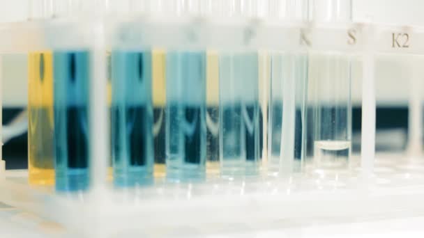Tubos de ensayo de laboratorio con sustancias químicas coloridas, primer plano de los tubos de ensayo en un bastidor con varias sustancias químicas de color en un laboratorio - Imágenes, Vídeo