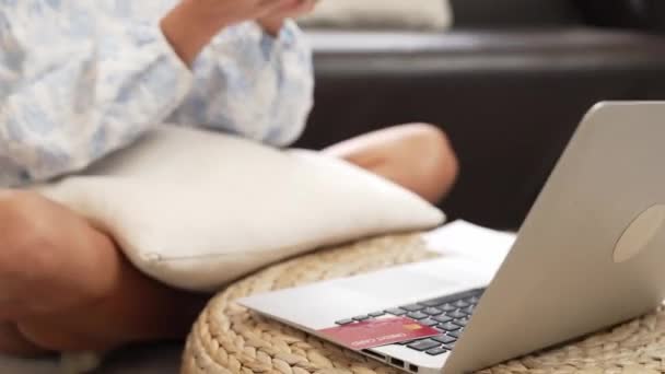 Молода жінка використовує ноутбук з кредитною карткою для інтернет-банкінгу, інтернет-магазин електронної комерції через онлайн платіжні шлюзи вдома. Сучасні та зручні онлайн покупки з дебетовою карткою. Блайт - Кадри, відео