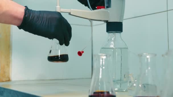 Manejo de matraz de laboratorio por científico, científico vertiendo sustancia del matraz al matraz en un laboratorio de química - Metraje, vídeo