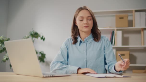 Egy komoly fiatal női irodai dolgozó jegyzetel, miközben egy laptopon dolgozik. Intelligens nő Otthonról dolgozik, Webináriumokat vagy Virtuális Oktatás Munkaórákat néz. Távmunka technológiai eszközei. - Felvétel, videó