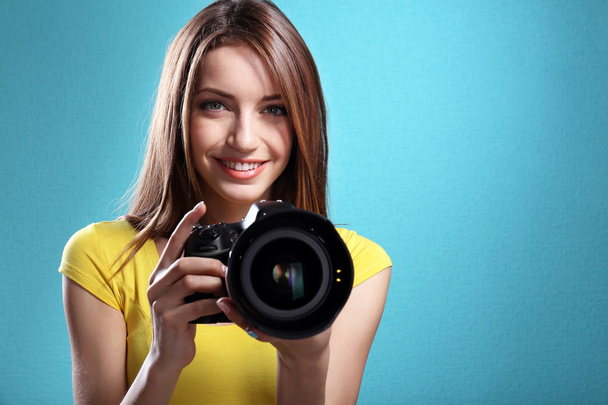 Young female photographer taking photos on blue background - Фото, зображення