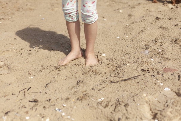 Pieni tyttö kävelee rannalla hiekalla kesällä. - Valokuva, kuva