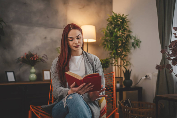 mladá dospělá žena jedna žena student číst knihu nebo studovat doma červené vlasy kopírovat prostor - Fotografie, Obrázek