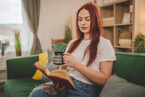 young adult woman one female student read book or study at home red hair copy space - Photo, Image