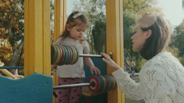 Felice ragazza prescolare sul campo da giuoco giocando con anelli colorati per contare sul parco giochi, il concetto di infanzia - Filmati, video