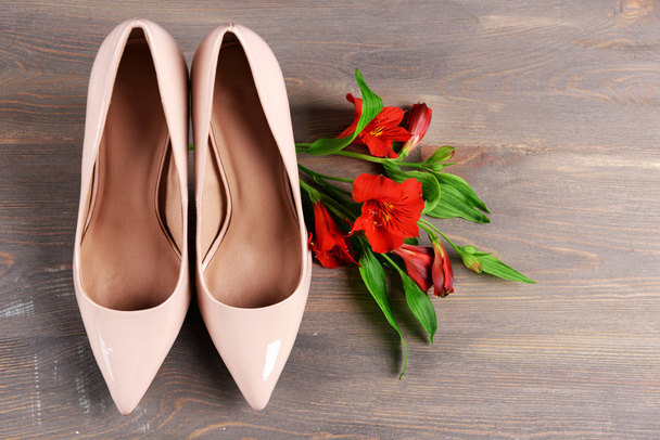 Female shoes with flowers on wooden background - Foto, imagen