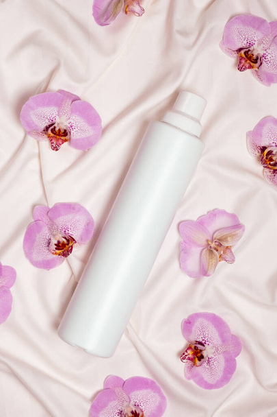 Líquido de lavado o suavizante de tela en ropa de cama con flores de orquídea, vista superior. - Foto, Imagen