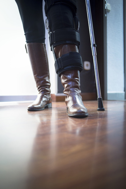 Lady walking on crutches in hospital clinic - Foto, imagen