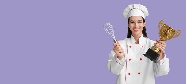 Chef femenino con copa de trofeo y batidor sobre fondo lila con espacio para texto - Foto, imagen